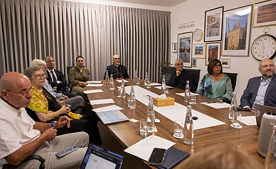 People gather around a conference table with a Notre Dame logo on the wall behind them.