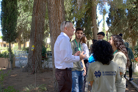 Man in white shirt talks to students wearing Notre Dame t-shirts outdoors